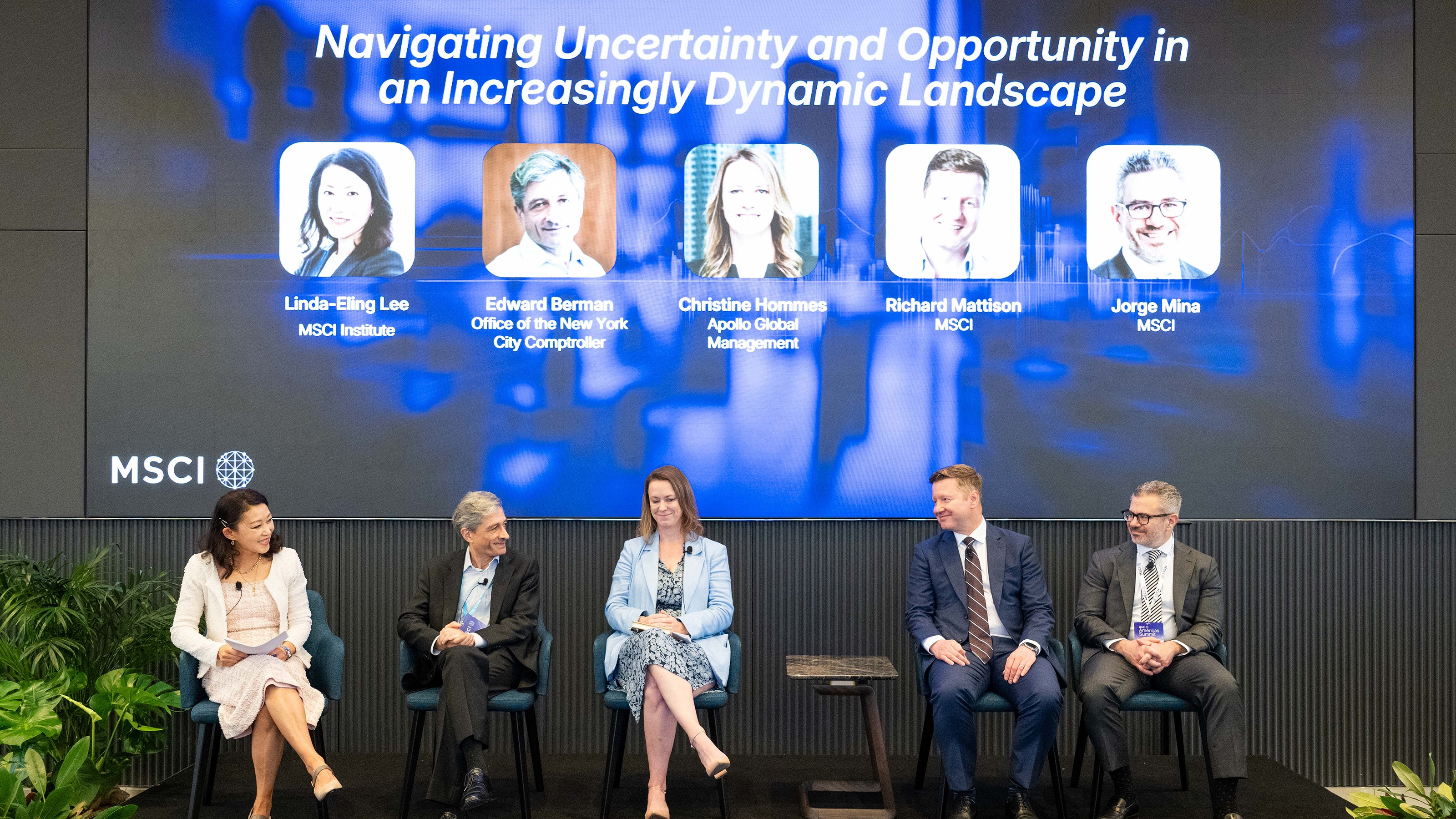 Panel of five speakers seated on stage under a screen showing their names at the MSCI conference.