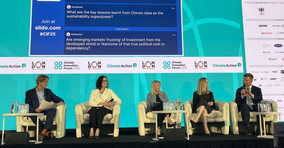 A panel of five individuals sits on stage at the Climate Innovation Forum 2025 in London. A large screen behind them displays audience questions via Slido, with branding from Climate Action and various sponsors visible.